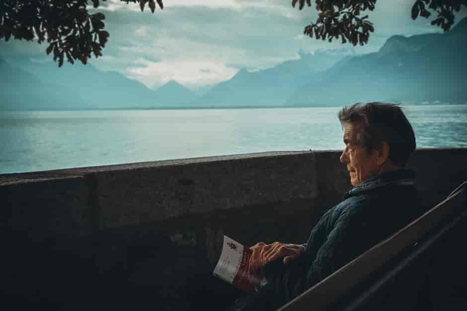 Man reading a book next to a lake