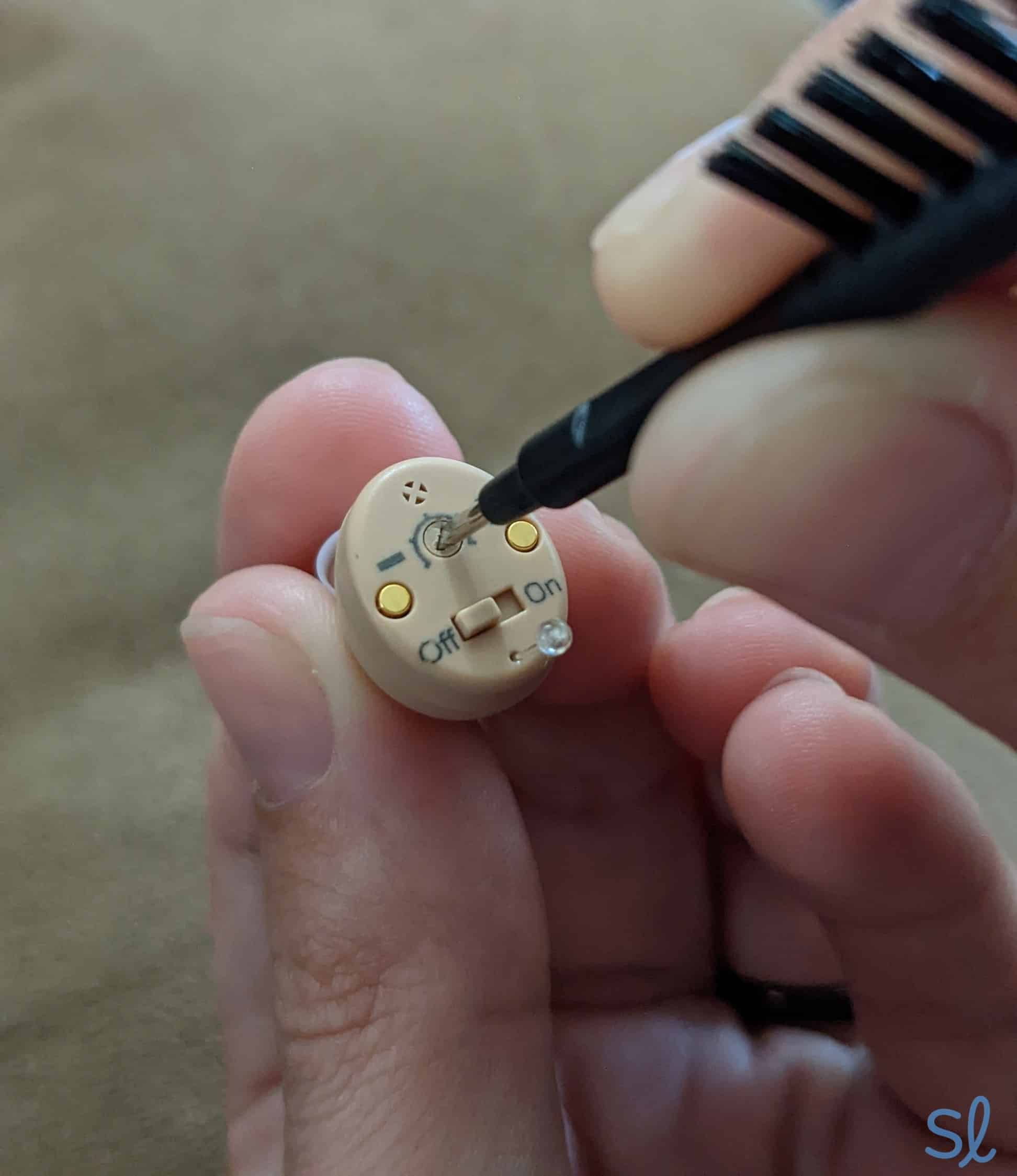 Adjusting the volume on the Atom hearing aid.