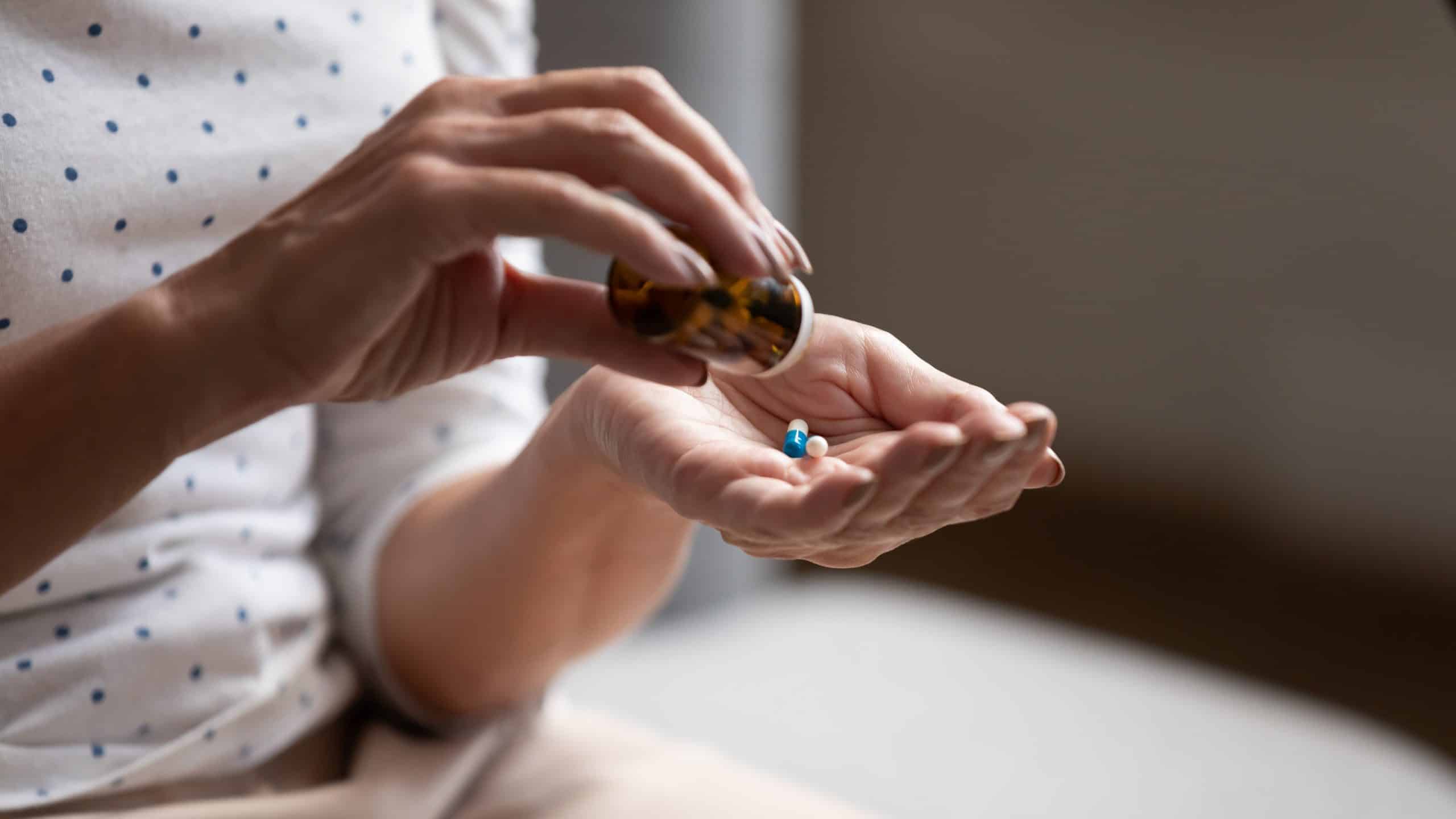 Person taking medications from bottle