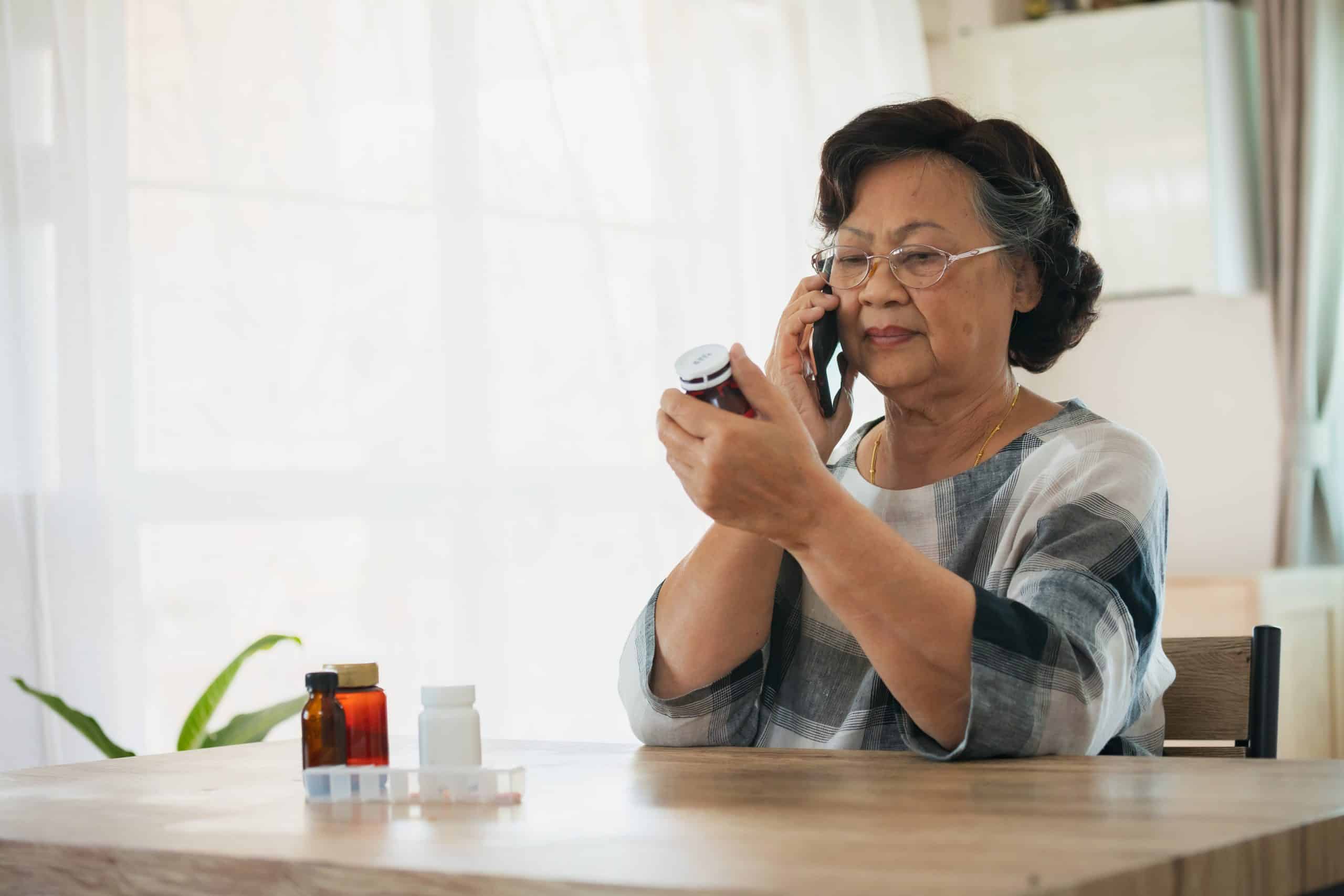 Senior woman on the phone and looking at medications