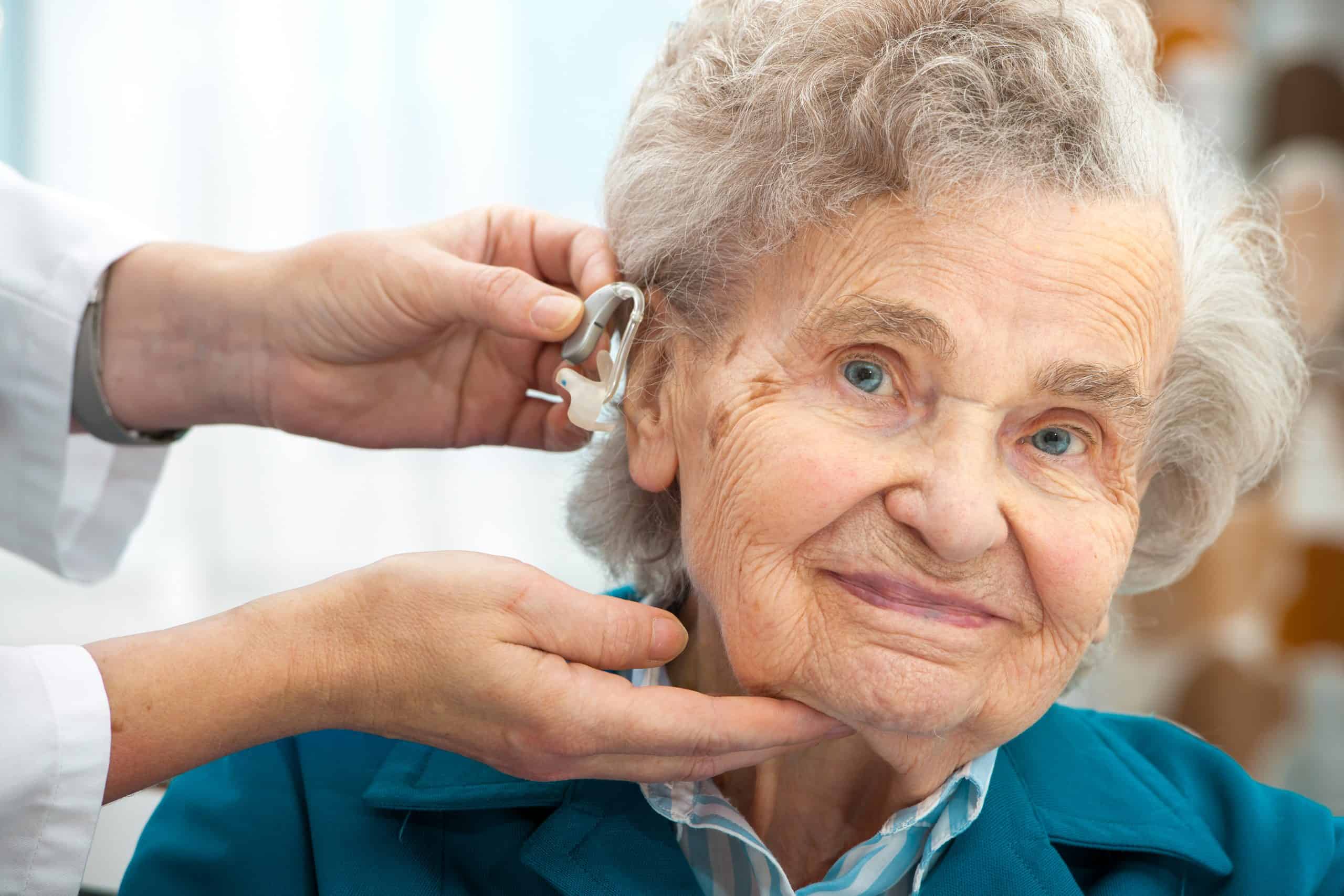 A doctor inserting a hearing aid on a senior
