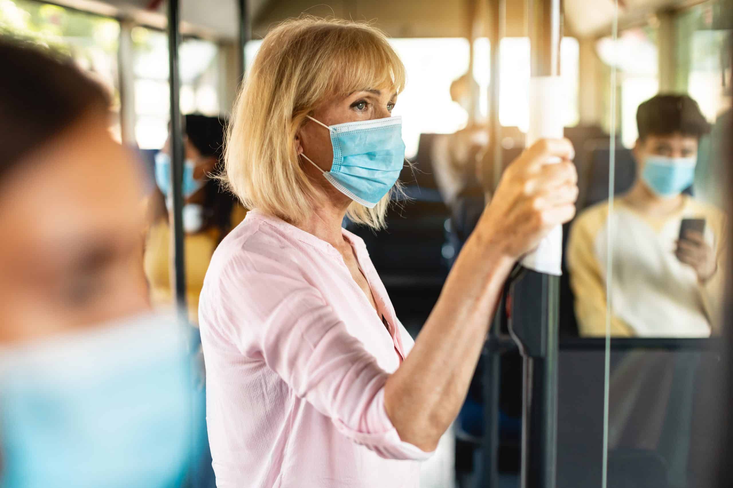 A woman wearing a medical mask on a bus