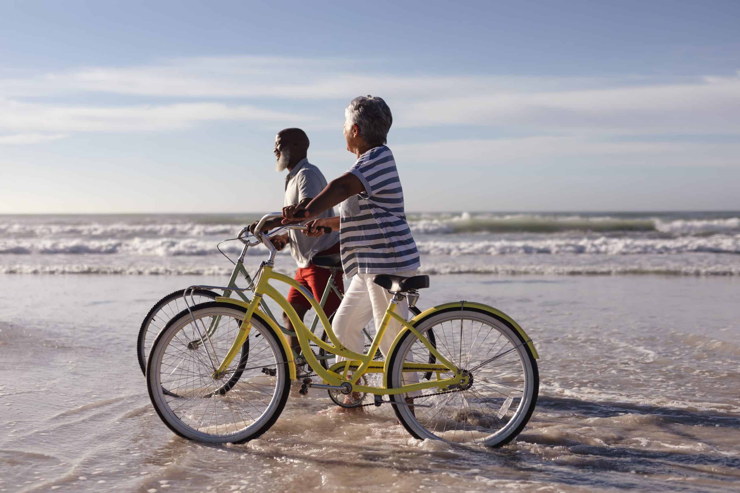 Senior couple riding bikes on the beach