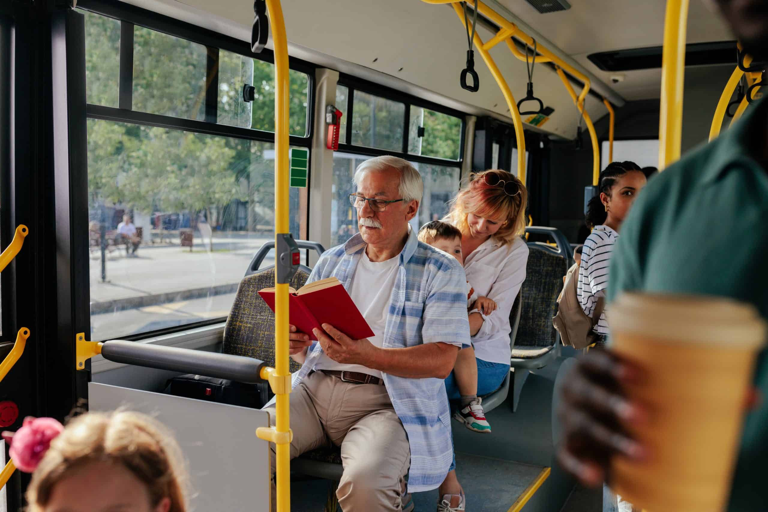 Senior reading a book on a bus